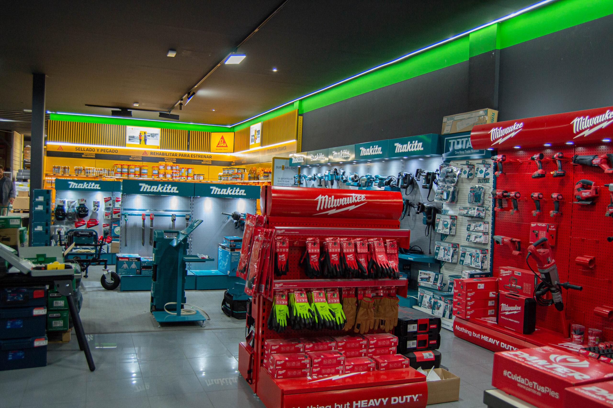 Exposición de herramientas profesionales Makita y Milwaukee en la tienda Ari Maquinaria de Córdoba, con zona de productos Sika y accesorios de construcción.