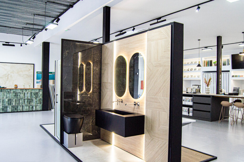 Baño moderno con lavabos suspendidos, espejos retroiluminados y revestimientos cerámicos en tonos madera y mármol. Diseño elegante en el showroom de Ari Ceramic Córdoba.